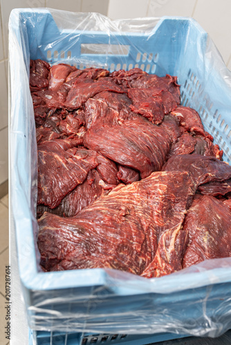 Raw beef meat in blue industrial plastic crate