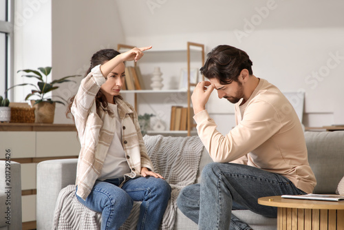 Unhappy man with his wife quarreling on sofa at home. Divorce concept
