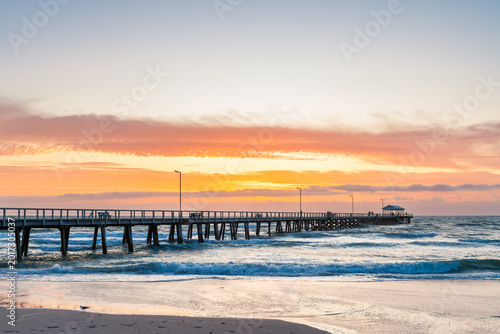 Foto People walking along Henley Beach Jetty during a stormy dramatic sunset viewed from the shoreline in Adelaide, South Australia