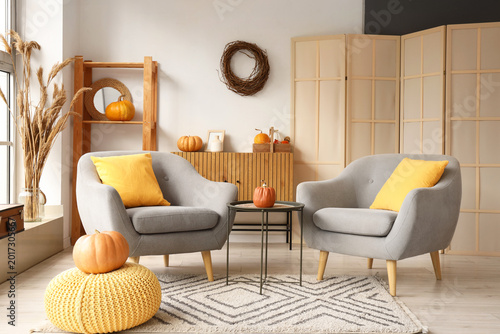 Photos Interior of modern living room decorated for autumn with comfortable armchairs,
