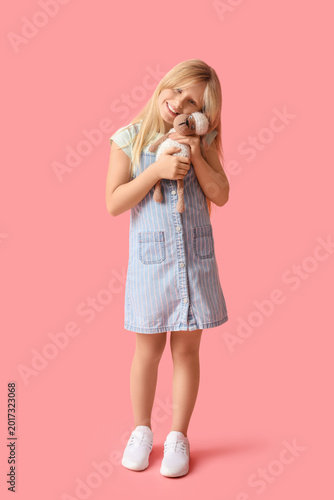 Cute little girl with plush sheep toy on pink background