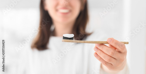 Φωτογραφία Woman with applied paste on bamboo tooth brush in bathroom, closeup