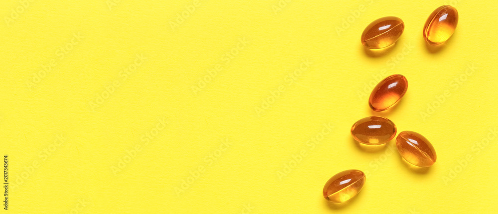 Obraz premium Vitamin E pills on yellow background, closeup