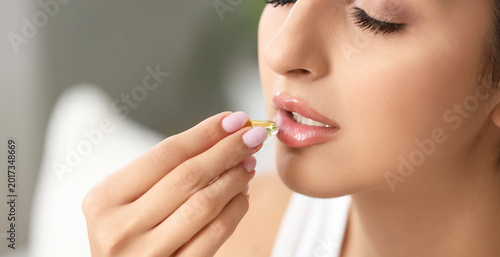 Young woman taking vitamin ...