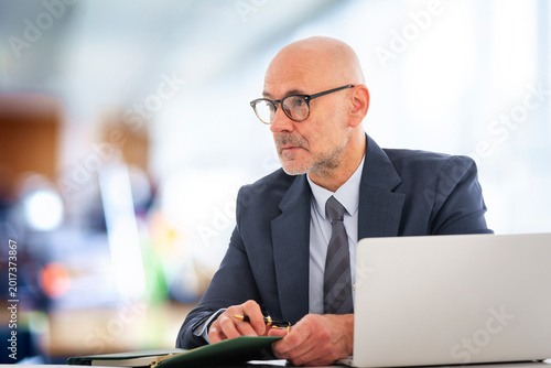 Middle-aged professional businessman sitting at the office and using his laptop