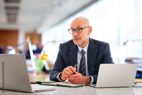 Middle-aged professional businessman sitting at the office and using his laptop