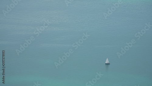 Solitary white sailboat on the vast turquoise waters of Lake Geneva, Switzerland - minimalist aerial view