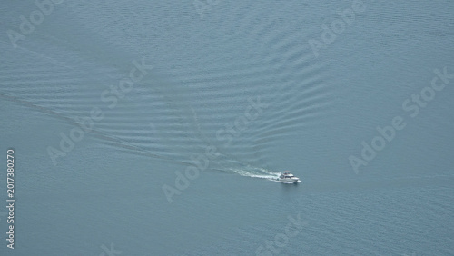 Aerial view of a solitary motorboat cruising on the calm blue water of Lake Geneva, Switzerland