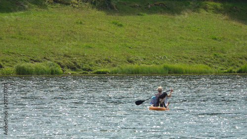 Femme faisant du stand-up paddle sur un lac avec son chien Border Collie
