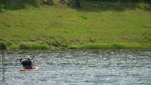 Femme faisant du stand-up paddle sur un lac avec son chien Border Collie