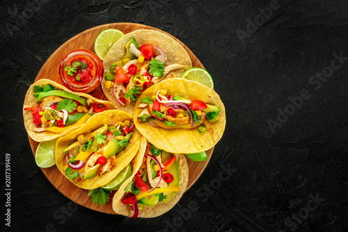 Mexican tacos with pulled chicken, avocado, chili peppers, and red salsa, overhead flat lay shot, with copy space