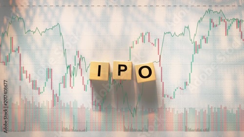 The acronym IPO Initial Public Offering is spelled out using three wooden letter blocks placed on top of a background featuring financial candlestick charts and graphs. 3D render animation