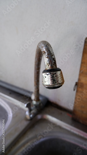 Obraz na płótnie a vertical close-up shot capturing a metal gooseneck kitchen faucet mounted on a stainless steel sink, suitable for plumbing and home repair concepts