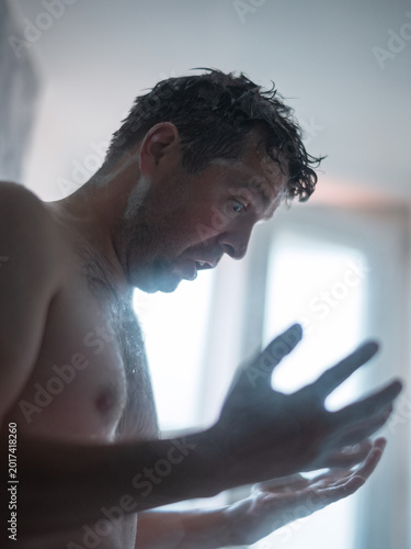 Vászonkép man standing in a modern shower feeling frustrated and anxious that the water h
