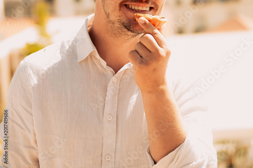 Foto Person eats snack outdoors while enjoying sunny weather in casual setting with buildings in  background during day