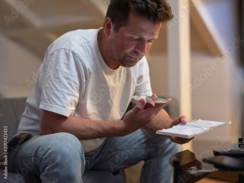 Man looking at a compact disc while sitting in a living room