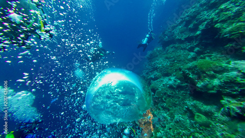 Foto Large air bubble rises beside scuba divers along a tropical reef wall