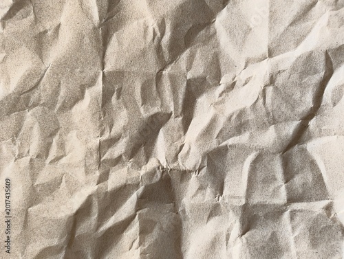 Crinkled brown paper texture with natural light and shadow creating depth for creative backgrounds
