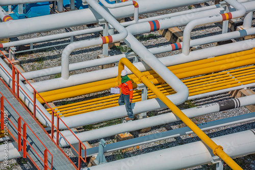 Valokuva Male worker inspection at steel long pipes and pipe elbow in station oil factory