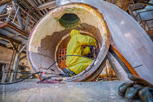 Male workers use high-pressure water jets to clean splashing the dirt of tube boilers in industrial areas or toxic hazardous material