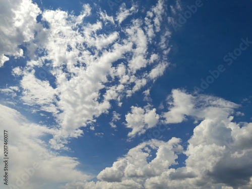 Beautiful white cumulus and altocumulus clouds on a bright blue sky background
