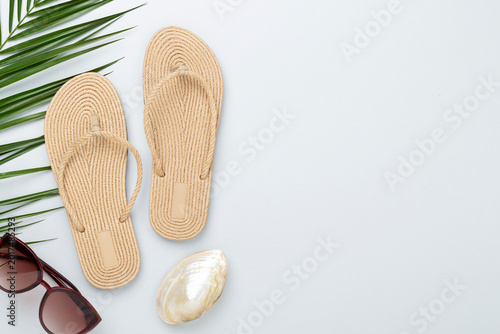Flip flops with summer accessories on color background, top view