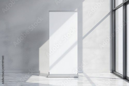 Roll up banner standee mockup standing upright on a smooth light grey wall in a modern corporate office lobby, plain white banner surface without text,