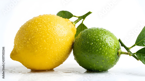 Fresh yellow lemon and green lime with water droplets and leaves isolated on a white background.