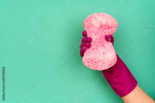 Foto Hand in pink cleaning glove holding soapy pink sponge