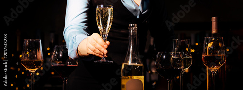 Professional sommelier holding glass of sparkling wine in bar. Selection and tasting of premium alcohol drinks.