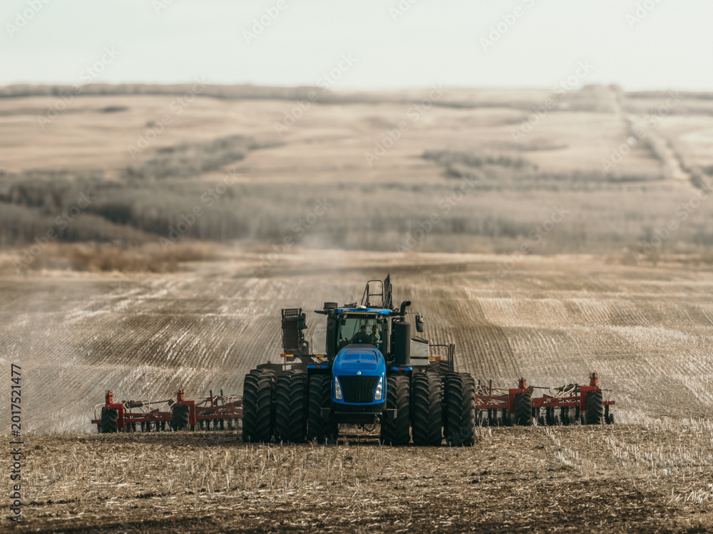 Fototapeta premium tractor pulling a seed drill and air seeder across a cultivated prairie field