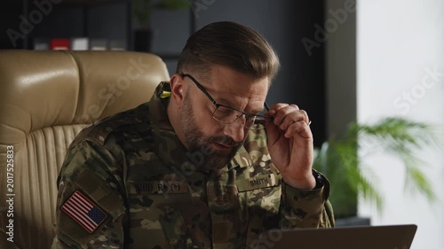 U.S. army officer overwhelmed with strategic decisions while working on laptop