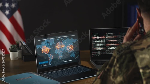 U.S. intelligence officer monitoring war zones on laptops while talking on phone