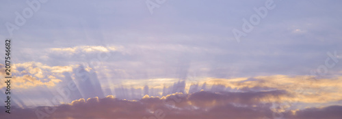 Foto Pastel sunrise sky with sun rays streaming above layered clouds at peaceful earl