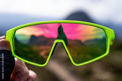 Close-up of bright neon cycling sunglasses reflecting a mountain landscape, premium gear, lifestyle accessory