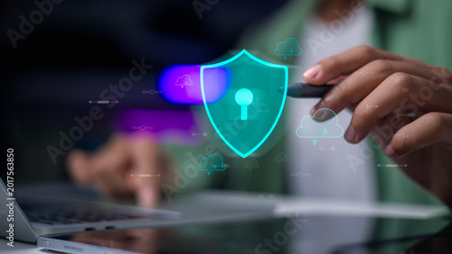 User holding pen pointing at virtual shield icon with cloud computing network for data security protection concept.