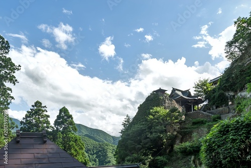 山形市 山寺にある立石寺の断崖絶壁に建つ納経堂と開山堂、夏の青空に映える荘厳な風景/The Nokyodo Hall and Kaizando Hall Standing on a Steep Cliff of Risshakuji Under a Summer Sky in Yamadera