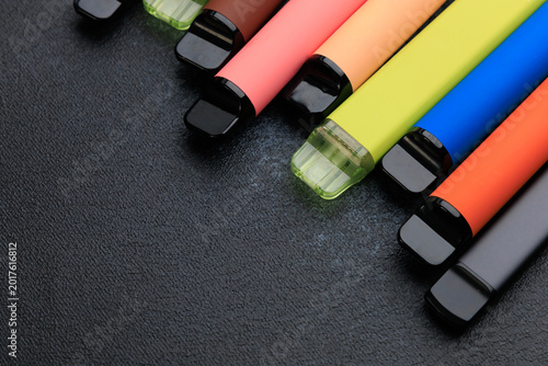 Quadro em tela Various electronic cigarettes arranged in different colors on a dark surface for
