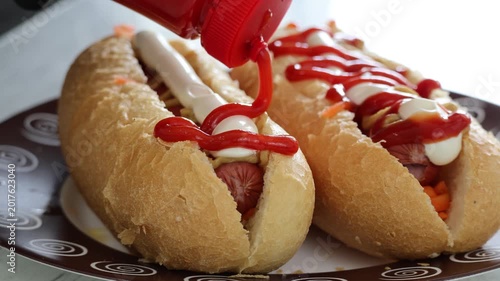Close-up of ketchup being squeezed onto hot dog