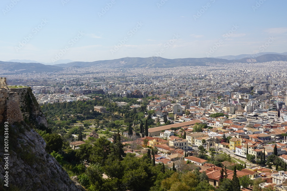 Obraz premium A panoramic view of the city of Athens, Greece, taken from the rock of the Acropolis, showing some of the neoclassical houses of the Plaka district and the dense urban fabric of the modern city