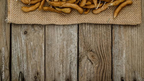 Foto Dried tamarind pods arranged on burlap on a wooden table with rustic texture in