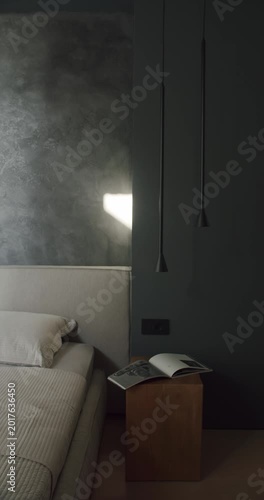 Modern bedroom interior design with dark gray walls, minimalist furniture, and ambient lighting. A wooden nightstand holds an open book, creating a cozy atmosphere.