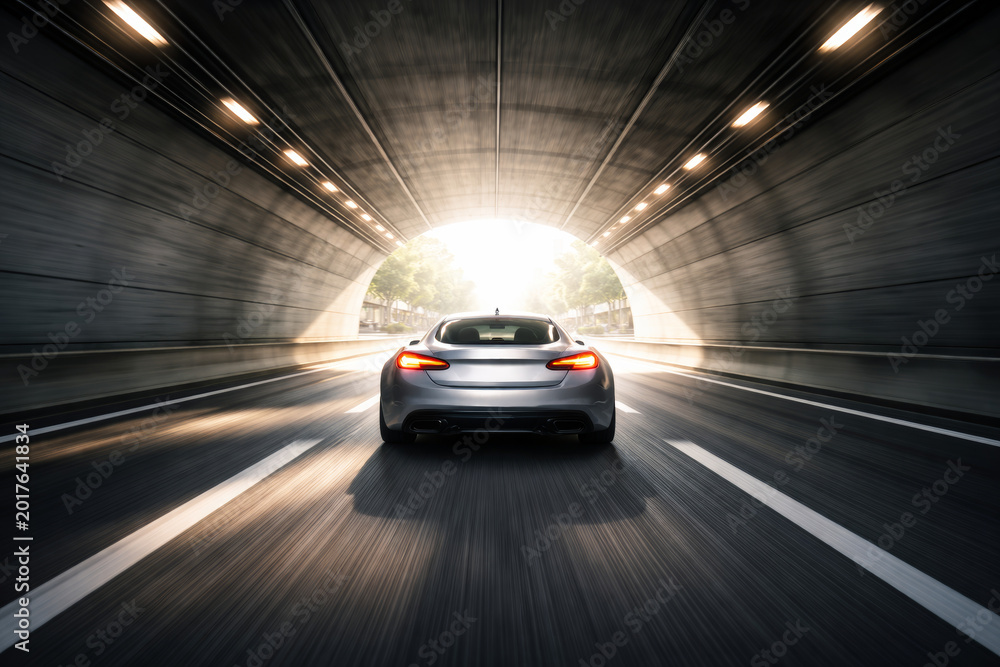 Fototapeta premium Car speeding through a tunnel towards bright daylight exit