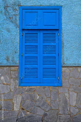 Blue wooden shuttered window on rustic textured wall