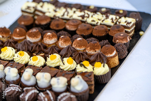 Elevated close-up view of assorted gourmet mini pastries and truffles on a slate platter