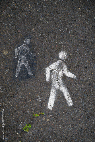Top view of stenciled white pedestrian walking symbols on dark asphalt with copy space