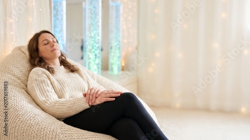 Woman resting with eyes closed in a sensory bean bag chair inside a softly lit snoezelen room — autism therapy and mental wellbeing concept