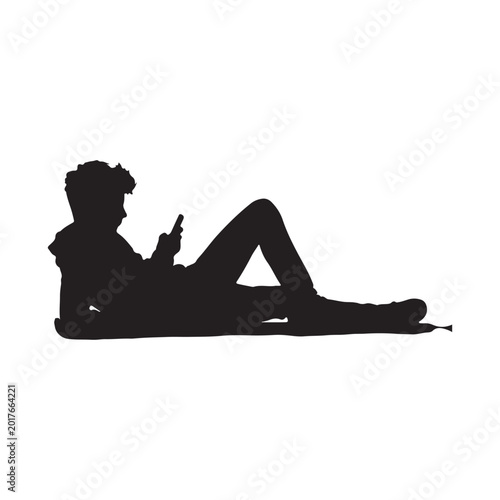 Silhouette of a teenager lying down using a smartphone des
