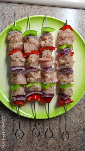 Raw marinated chicken skewers with peppers and onions on plate