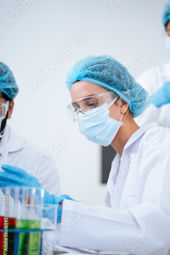 Expert female researcher performing clinical trials for a new antiviral cure, carefully analyzing biochemical samples to stop a global pandemic virus within a pharmaceutical science laboratory